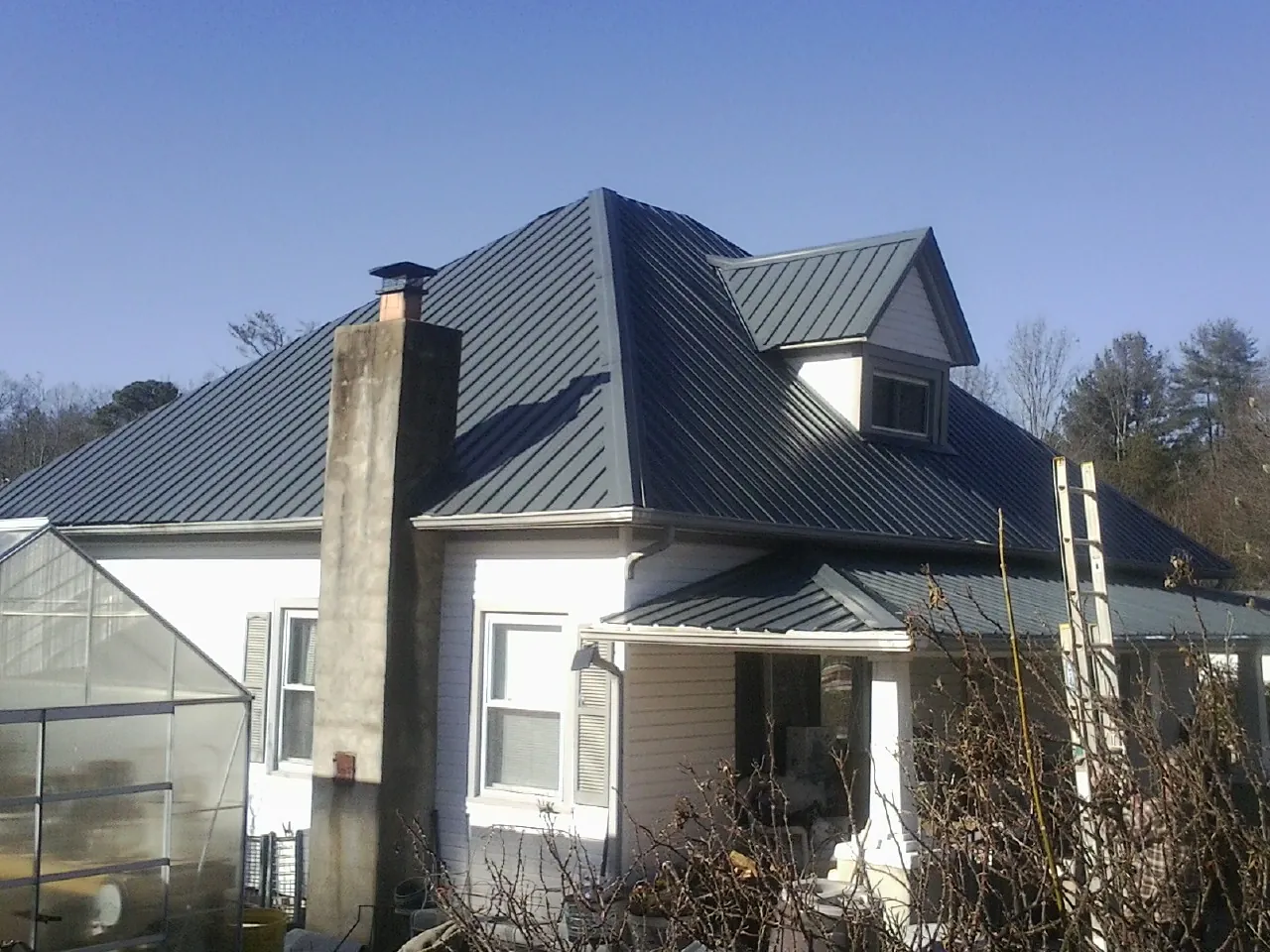 Dark blue standing seam metal roof on a white farmhouse with dormer — Slate & Tile Roof Repair by Roofing Brothers in Rossiter