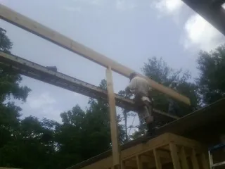 Carpenter setting a ridge beam over a new addition frame — Ice Dam Removal by Roofing Brothers in Rossiter