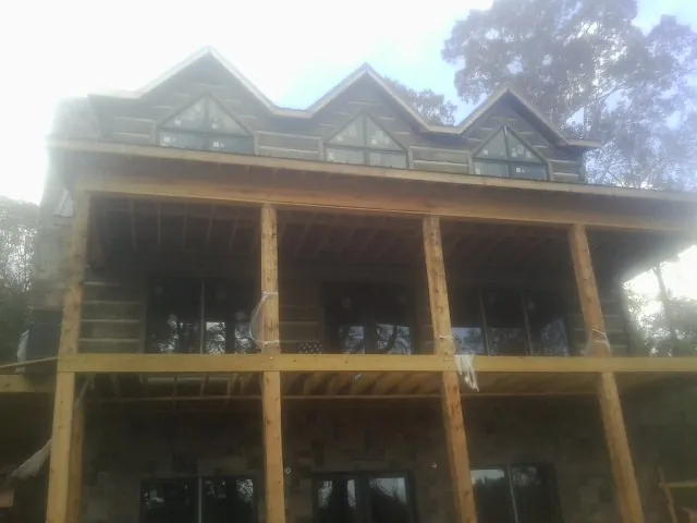 Dormers and porch framing on a large log home under construction — Roof Coating work by our crew in Rossiter