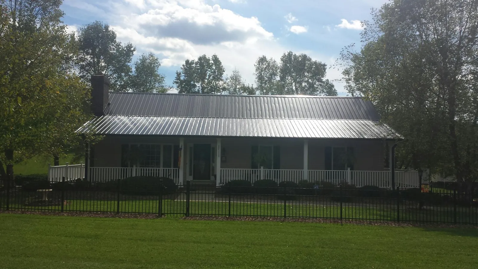Gray metal roof on a brick ranch with a full width front porch — Gutter Guard Installation work by our crew in Rossiter