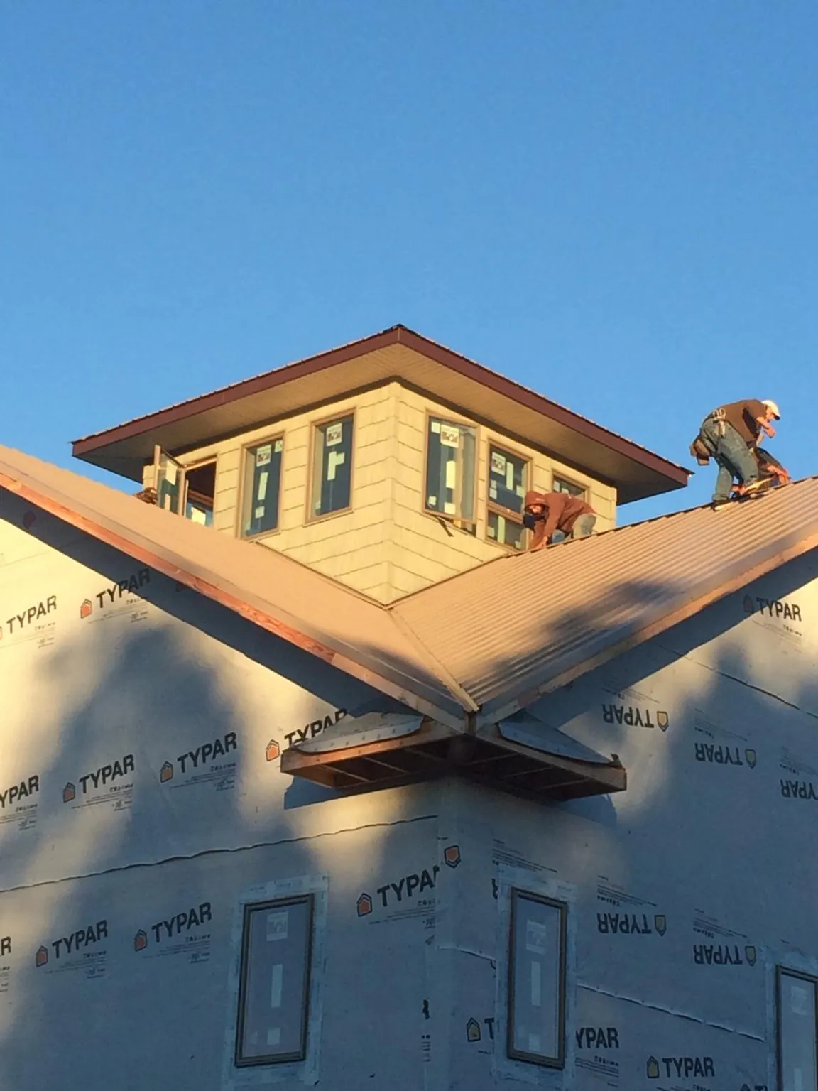 Roofers working around a rooftop cupola on a new metal roof at sunset — Roof Waterproofing in Rossiter by Roofing Brothers